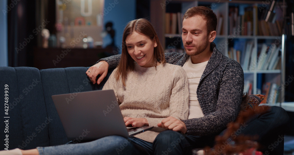 Caucasian attractive married couple in love using laptop computer choosing movie to watch communicating spending Valentine s day dating together. Caucasian attractive married couple in love using laptop computer choosing movie to watch communicating spending Valentine s day dating together.