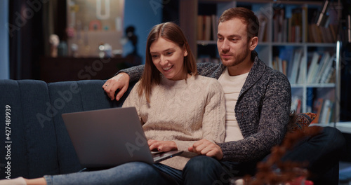 Caucasian attractive married couple in love using laptop computer choosing movie to watch communicating spending Valentine s day dating together.