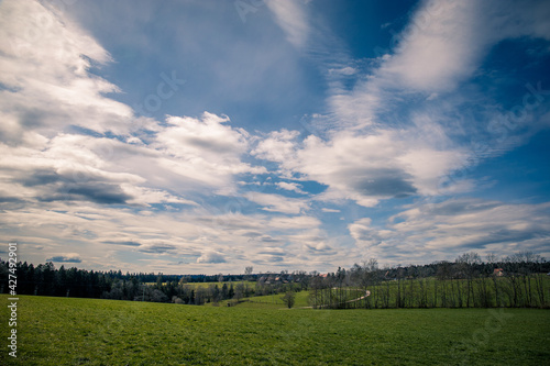 Wide view over the meadow valley with a blue and white cloudy sky