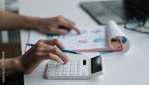 Close up businessman using calculator for analysis maketing plan, Accountant calculate financial report, computer with graph chart. Business, Finance and Accounting concept.