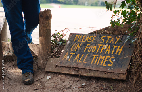 Country walker crossing a style next to a signpost