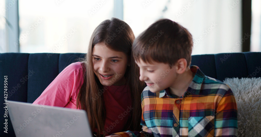Couple of lovely young siblings staying home playing on laptop video games together. teenage brother and sister. Technology addiction. Couple of lovely young siblings staying home playing on laptop video games together. teenage brother and sister. Technology addiction.