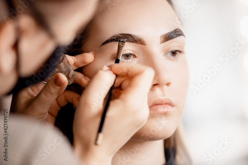 Eyebrow tint, master correction of brow hair women in beauty salon
