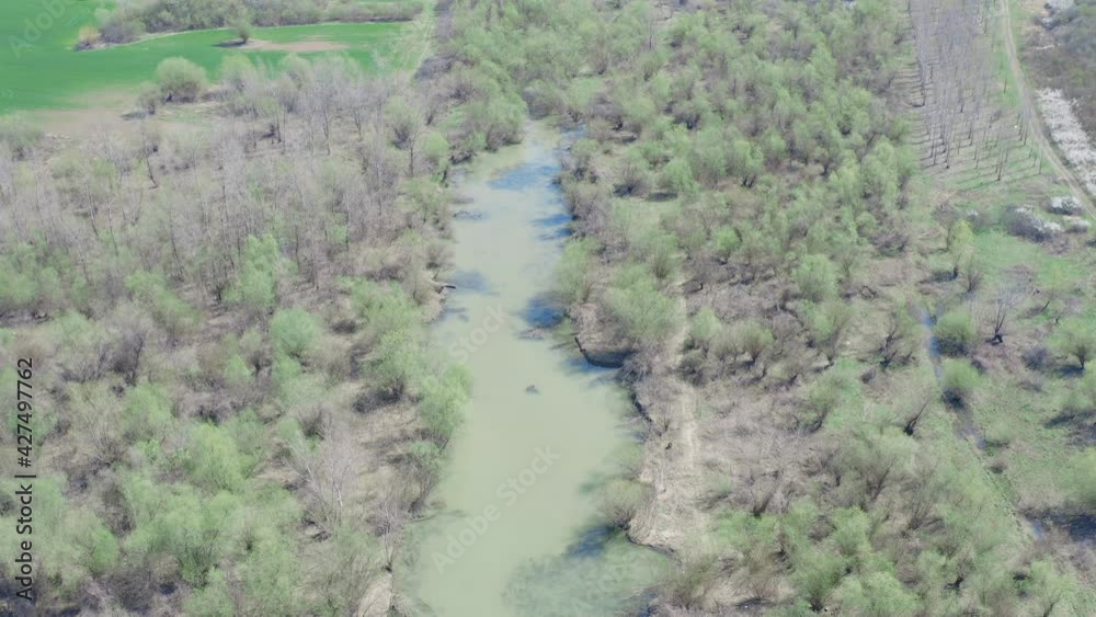 Flying with a camera drone high above a murky wild river surrounded by a thick tree line in the middle of nowhere on a cloudy day Flying with a camera drone high above a murky wild river surrounded by a thick tree line in the middle of nowhere on a cloudy day