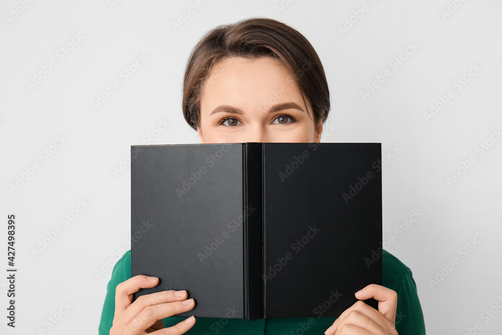 Beautiful young woman with book on light background Beautiful young woman with book on light background
