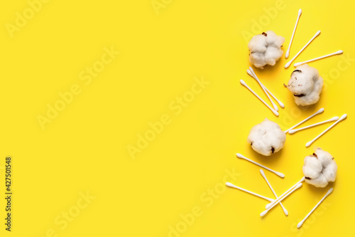 Cotton swabs and flowers on color background