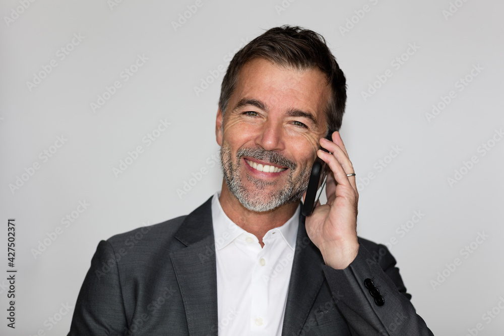 Handsome Mature Happy Man Smiling At The Camera. He is on a phone. Good news. Isolated on white Handsome Mature Happy Man Smiling At The Camera. He is on a phone. Good news. Isolated on white