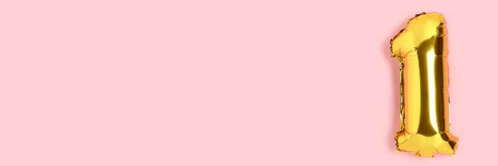 Banner with number 1 golden balloon with copyspace. One year anniversary celebration concept on a pink background.
