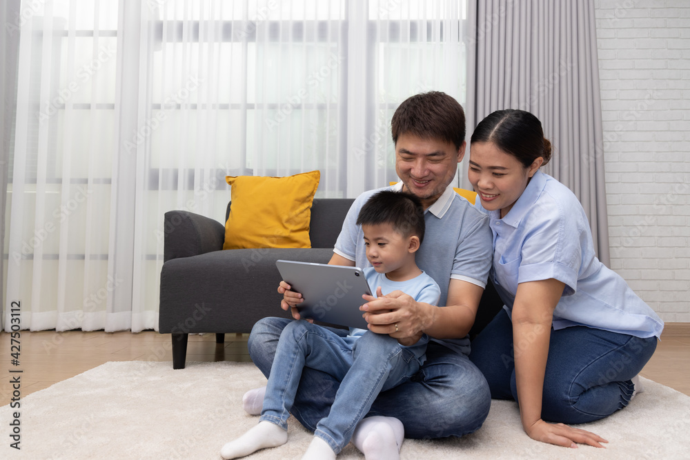 Portrait of happy Asian family with son using tablet in living room at home, Playing game or watching movies, Lifestyle relaxing together concept Portrait of happy Asian family with son using tablet in living room at home, Playing game or watching movies, Lifestyle relaxing together concept