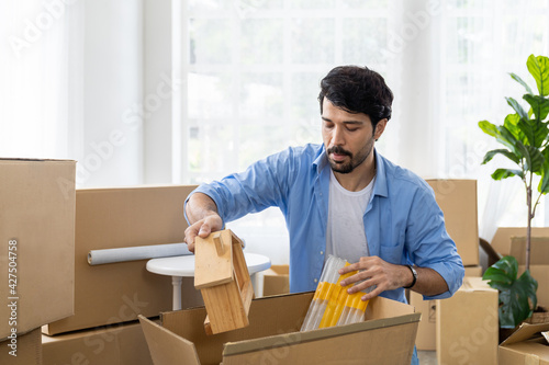 Adult man with mustache and beard packaging cardboard boxes for moving into a new house