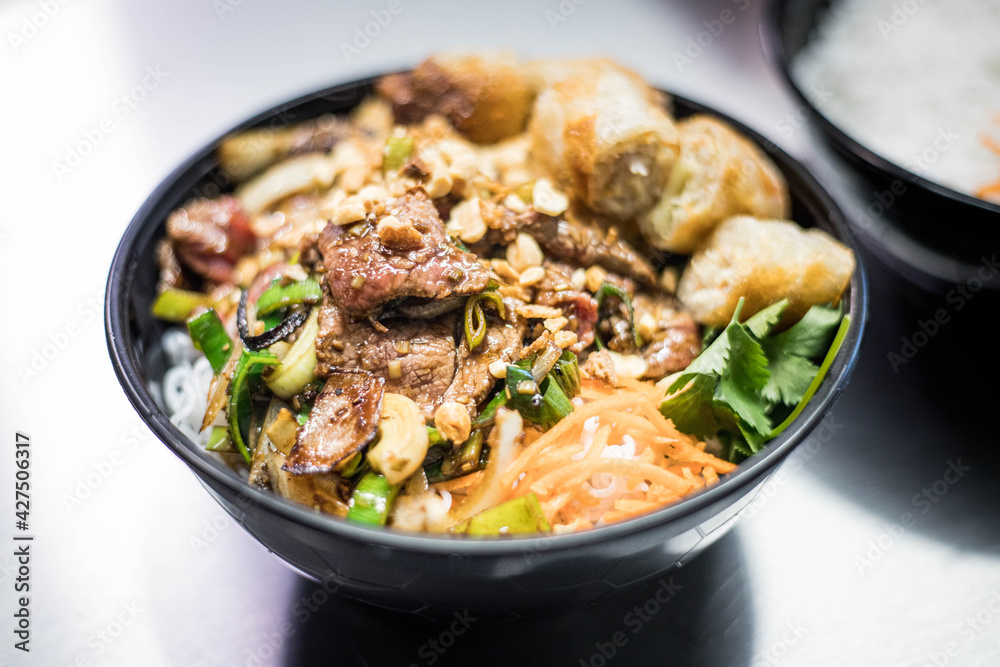 Salade de Nems avec des pat thaïlandaise dans un bol noir dans un restaurant asiatique Salade de Nems avec des pat thaïlandaise dans un bol noir dans un restaurant asiatique