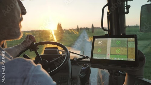 farmer male driving tractor uses smart display touch screen application to check the fields of the farm,agriculture new technology app onboard of agricultural machine,modern farmhouse startup photo