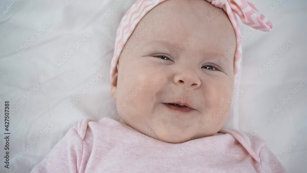 top view of cheerful baby smiling while looking at camera in bed. top view of cheerful baby smiling while looking at camera in bed.