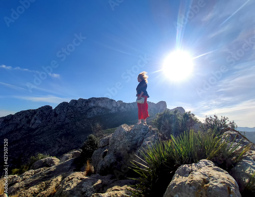 mature redhead woman backlight with wind-blown hair on the mountain Cim Penya Roja, Els Poblets, Alicante, Spain photo