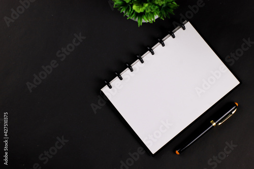 White paper book and pen on black table