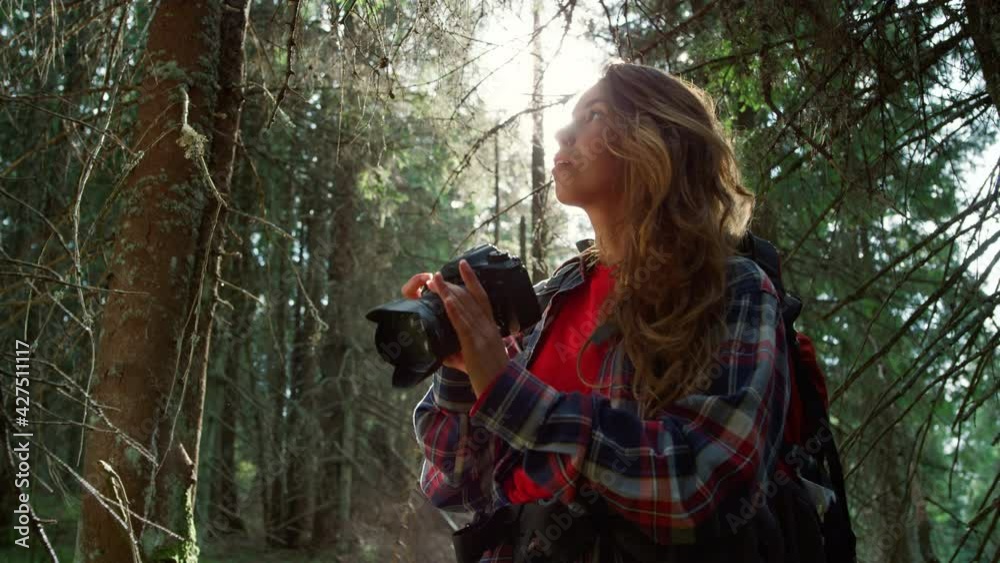 Woman taking photos on camera in forest. Tourist adjusting zoom on camera lens 