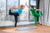 Two mature female friends exercise yoga together