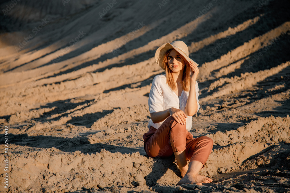 Young beautiful lonely woman with long hair with straw hat. A lonely girl goes down the sand dunes. Summer fashion poartrait outdoor. Young beautiful lonely woman with long hair with straw hat. A lonely girl goes down the sand dunes. Summer fashion poartrait outdoor.