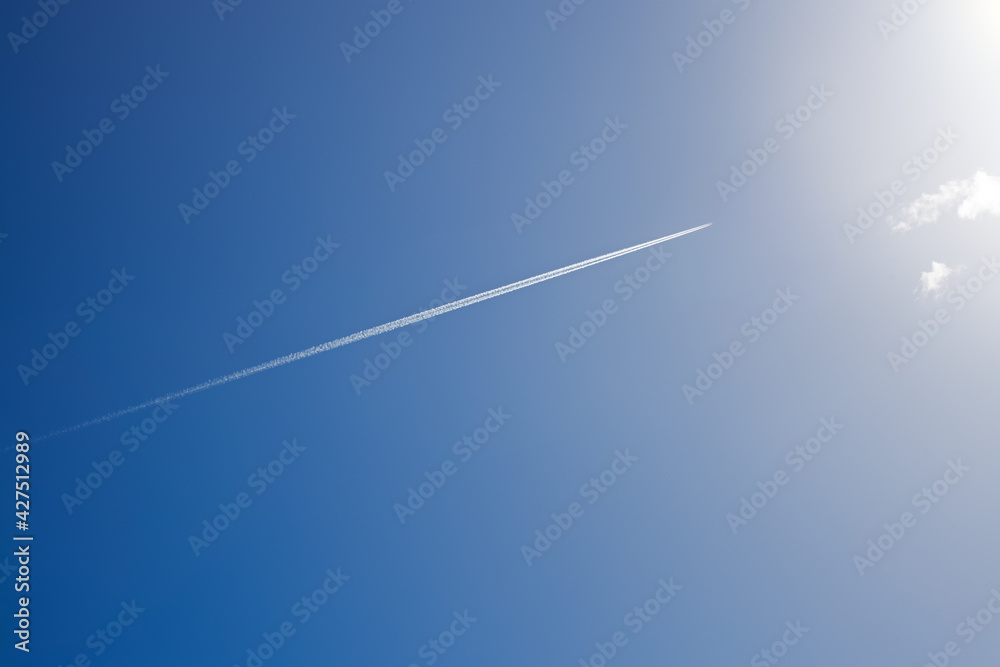 white trail from a military aircraft high in the blue sky, supersonic fighter in flight on a sunny day white trail from a military aircraft high in the blue sky, supersonic fighter in flight on a sunny day