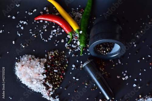 coarse salt and peppercorns, and chili pods on a black background