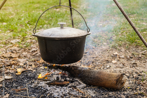 Cooking in a cauldron on an open fire. A camping trip with outdoor cooking.