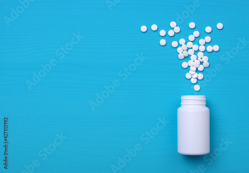 Pills, tablets and bottle on blue background. © Alekss