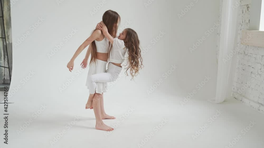 little girls with long hair in white clothes play, indulge, do acrobatic tricks