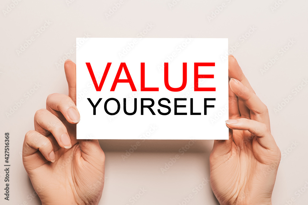 Female hands hold card paper with text value yourself on a yellow background. Business and finance concept Female hands hold card paper with text value yourself on a yellow background. Business and finance concept