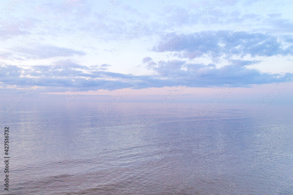 Calm water on sea surfase. Colorful clouds on sunset. Warm evening on beach. Summer mood. Scenery view. Baltic Sea in Jurmala resort, Latvia.