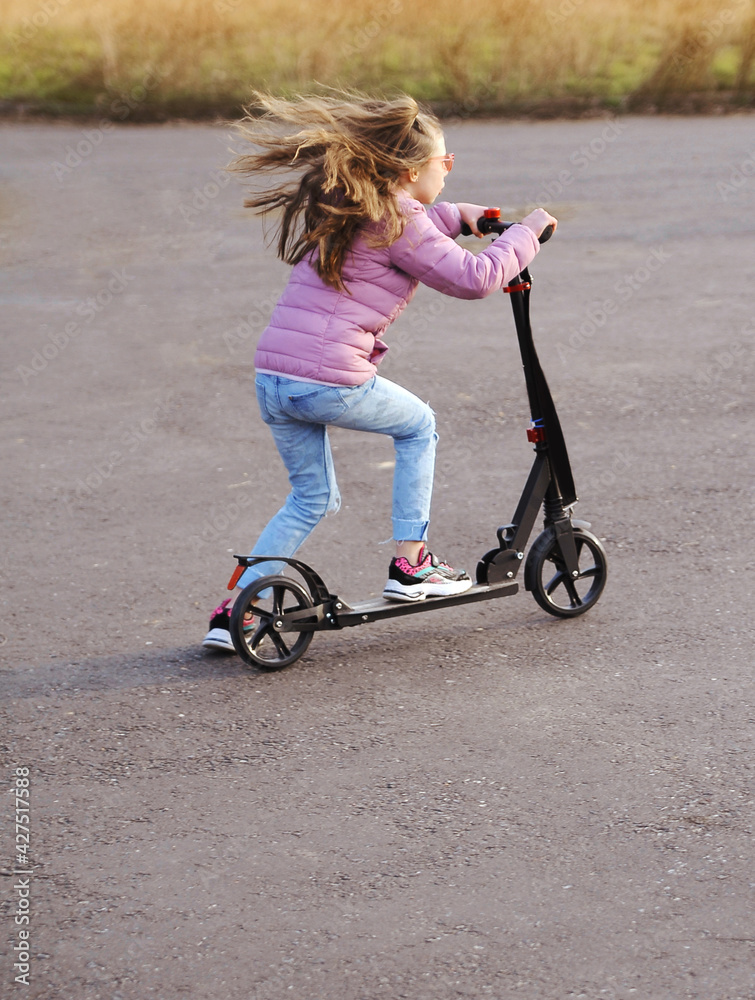 Little girl riding a scotter outdoor. Concept of healthy life. Little girl riding a scotter outdoor. Concept of healthy life.