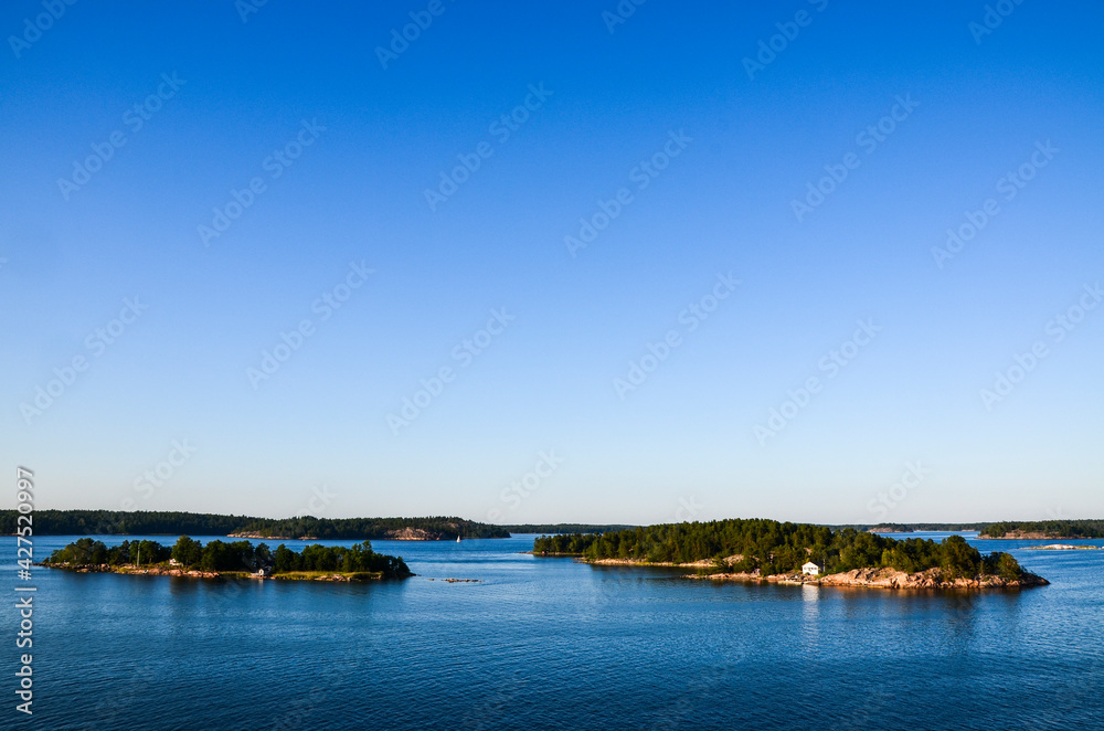 Rocky islands of Stockholm archipelago in Baltic sea with picturesque vacation houses and boats at sunset evening. Scandinavian landscape 