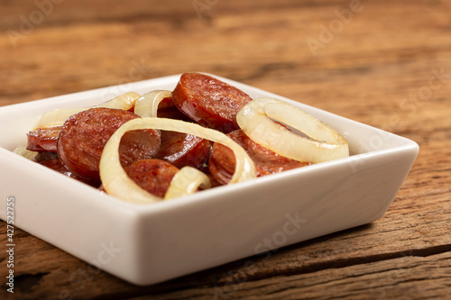 Sliced ​​calabrese sausage with onion on wooden background. photo