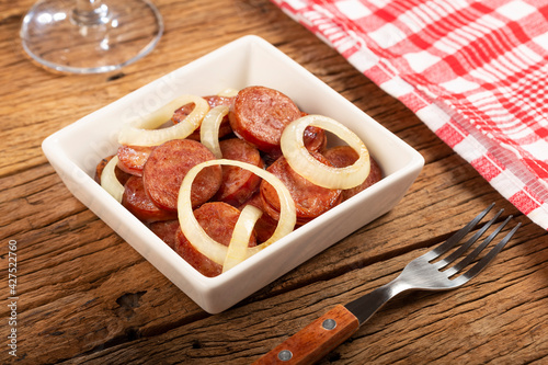 Sliced ​​calabrese sausage with onion on wooden background. photo