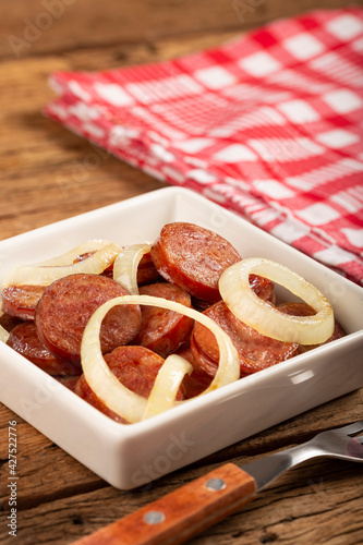 Sliced ​​calabrese sausage with onion on wooden background. photo