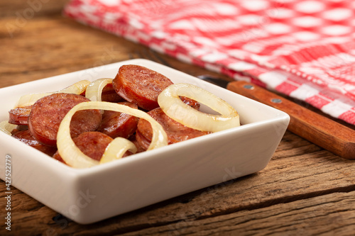 Sliced ​​calabrese sausage with onion on wooden background. photo