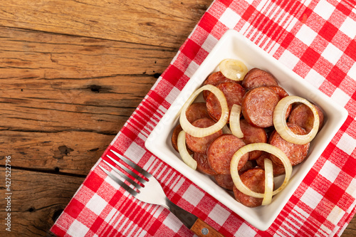 Sliced ​​calabrese sausage with onion on wooden background. photo
