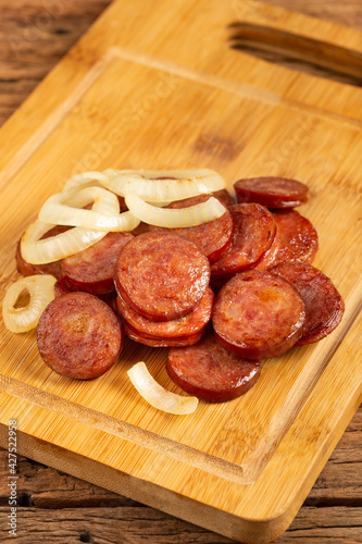 Sliced ​​calabrese sausage with onion on wooden background. photo