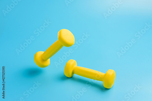 Two yellow dumbbells on a blue background.