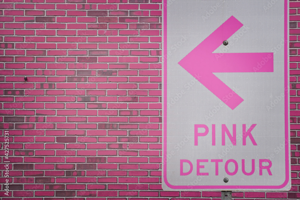 Obraz premium Pink detour sign in front of pink brick wall