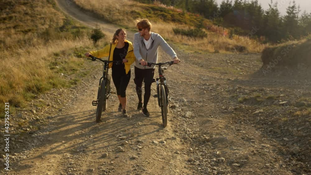 Girl and guy with bikes going on road Cyclists taking rest after exercising 