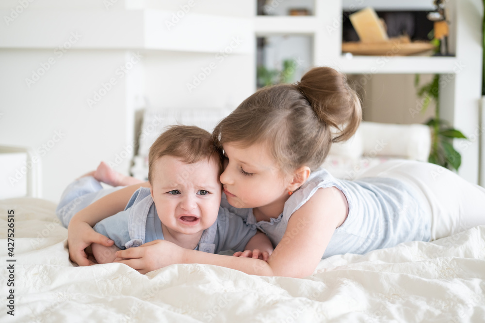 cute little girl older sister comforting her crying baby boy brother at home cute little girl older sister comforting her crying baby boy brother at home