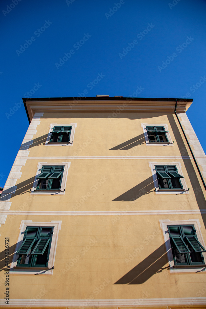 Fragments of Italian streets. The yellow facade of the building with green shutters on the windows.