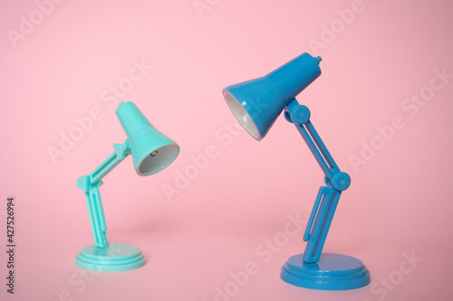 Closeup of mini mint and blue modern desk lamps on pink background