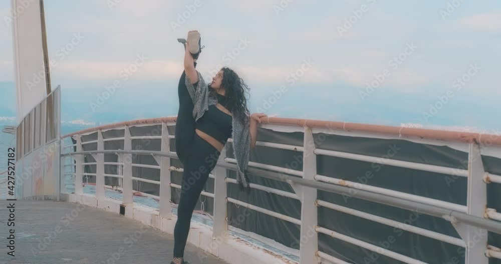 Flexible young dancer woman is stretching herself on bridge with beautiful sky and sea landscape. Sportive young lady, ballet. Flexible young dancer woman is stretching herself on bridge with beautiful sky and sea landscape. Sportive young lady, ballet.