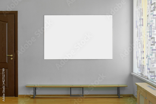 Empty white sign board hangs on concrete wall of gym indoor.