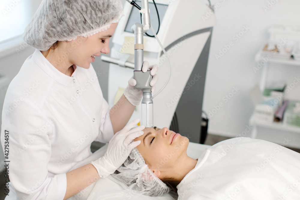 Fototapeta premium Cosmetology. Closeup Of Female Face having facial treatment in beauty salon. Cosmetic procedures in spa clinic. High quality photo