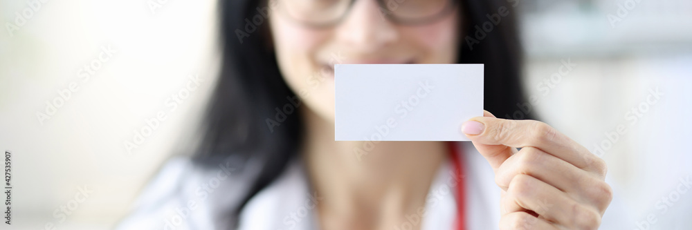 Smiling doctor portrait holding white business card in hand Smiling doctor portrait holding white business card in hand
