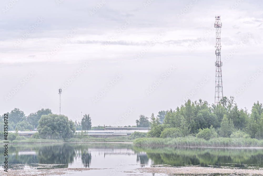 industrial zone and communication towers on the shore of the lake on a foggy morning