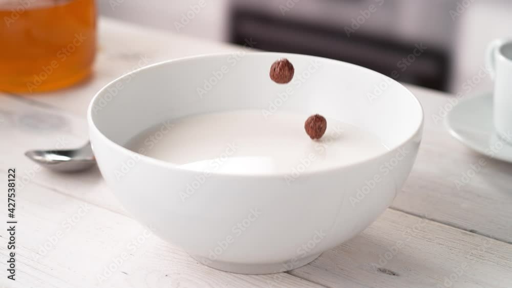 Chocolate Ball-Shaped Cereals Falling into White Bowl Filled with Milk in Slow Motion (Phantom Flex) Chocolate Ball-Shaped Cereals Falling into White Bowl Filled with Milk in Slow Motion (Phantom Flex)