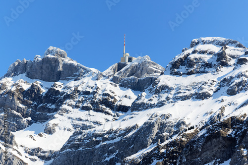 impressive säntis mountain during the day with bright sunshine and beautiful blue cloudless sky, with the transmission tower for telecommunication and radio can be seen on the summit, close up view